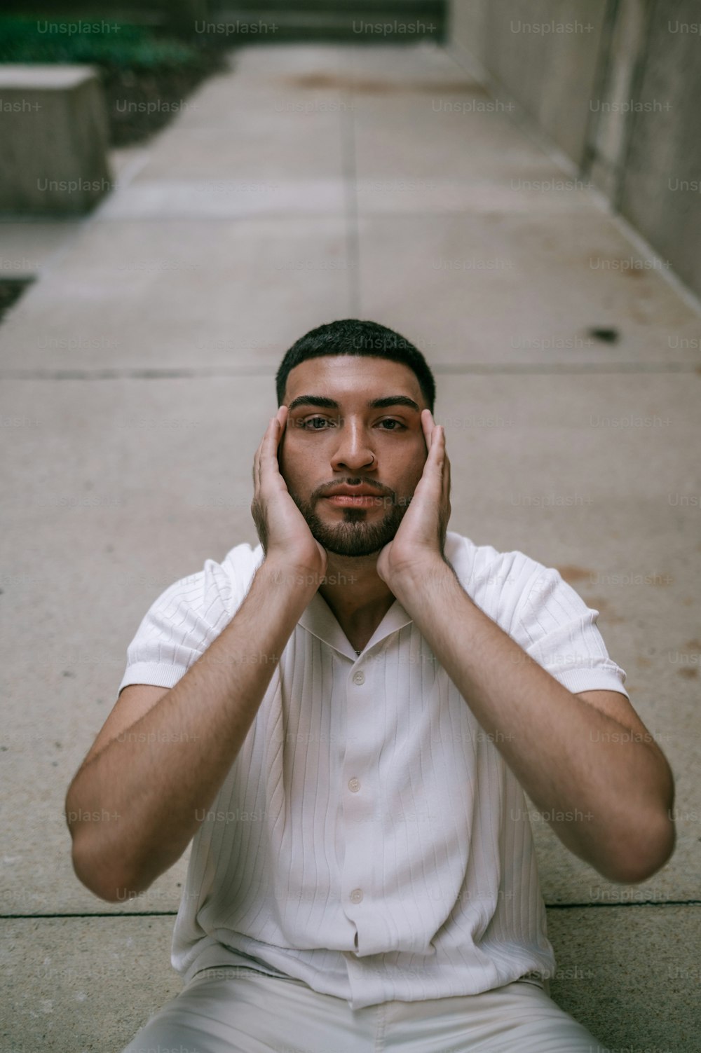 a man sitting on the ground holding his hands to his ears