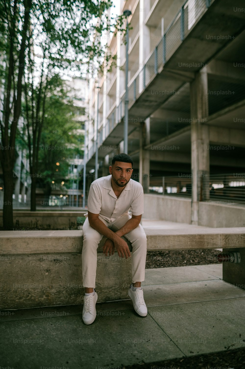 Un uomo seduto su una sporgenza di fronte a un edificio
