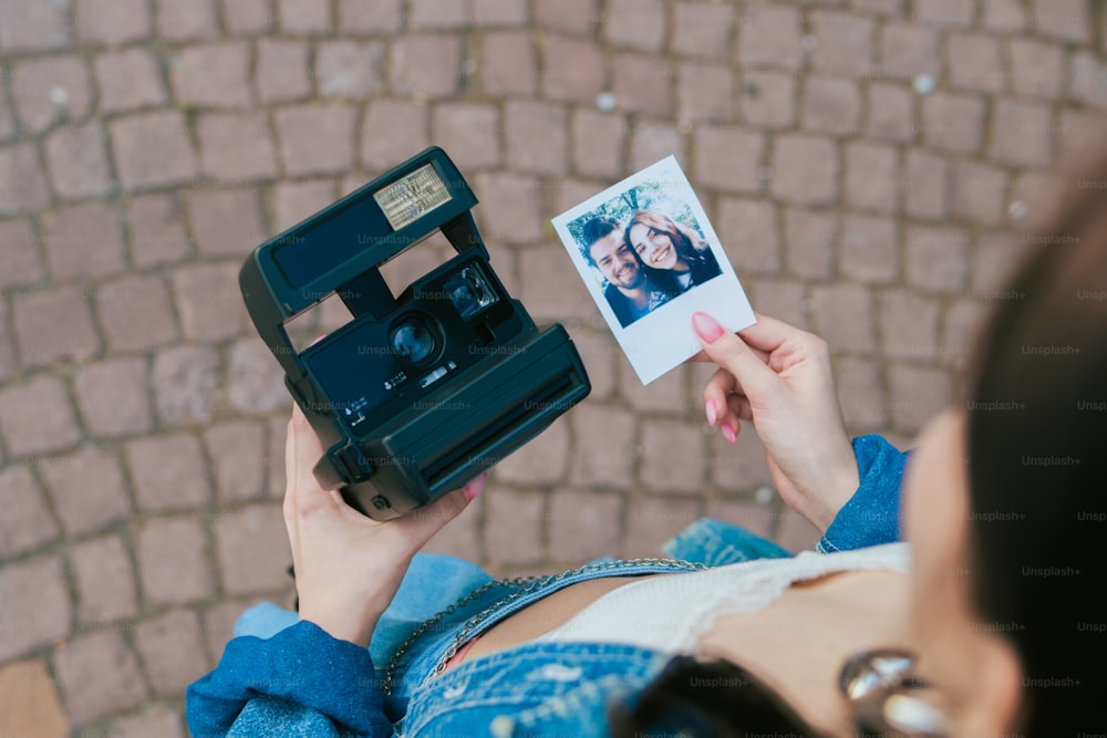 Una mujer sosteniendo una cámara Polaroid y una tarjeta Polaroid