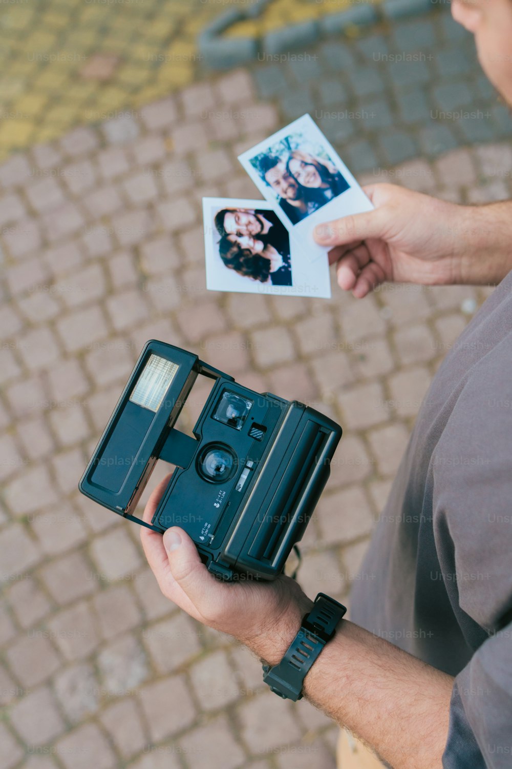 a man holding an old fashioned camera and a polaroid
