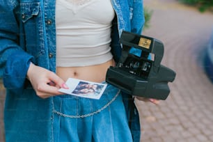 Una mujer sosteniendo una cámara y una polaroid