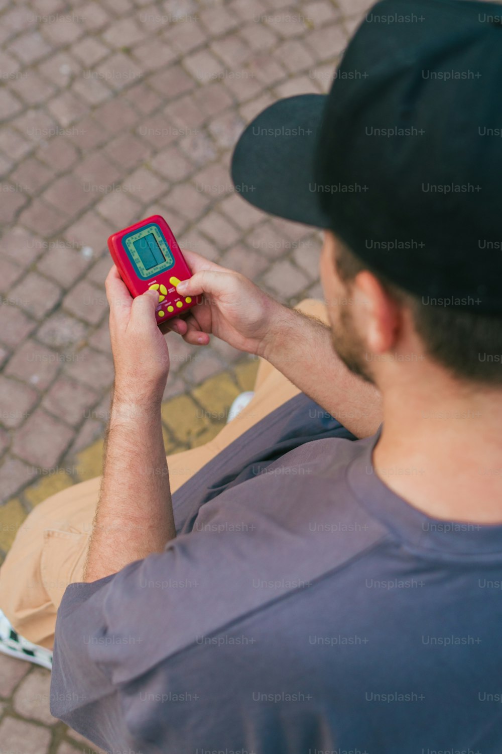 a man sitting on a bench looking at a red electronic device