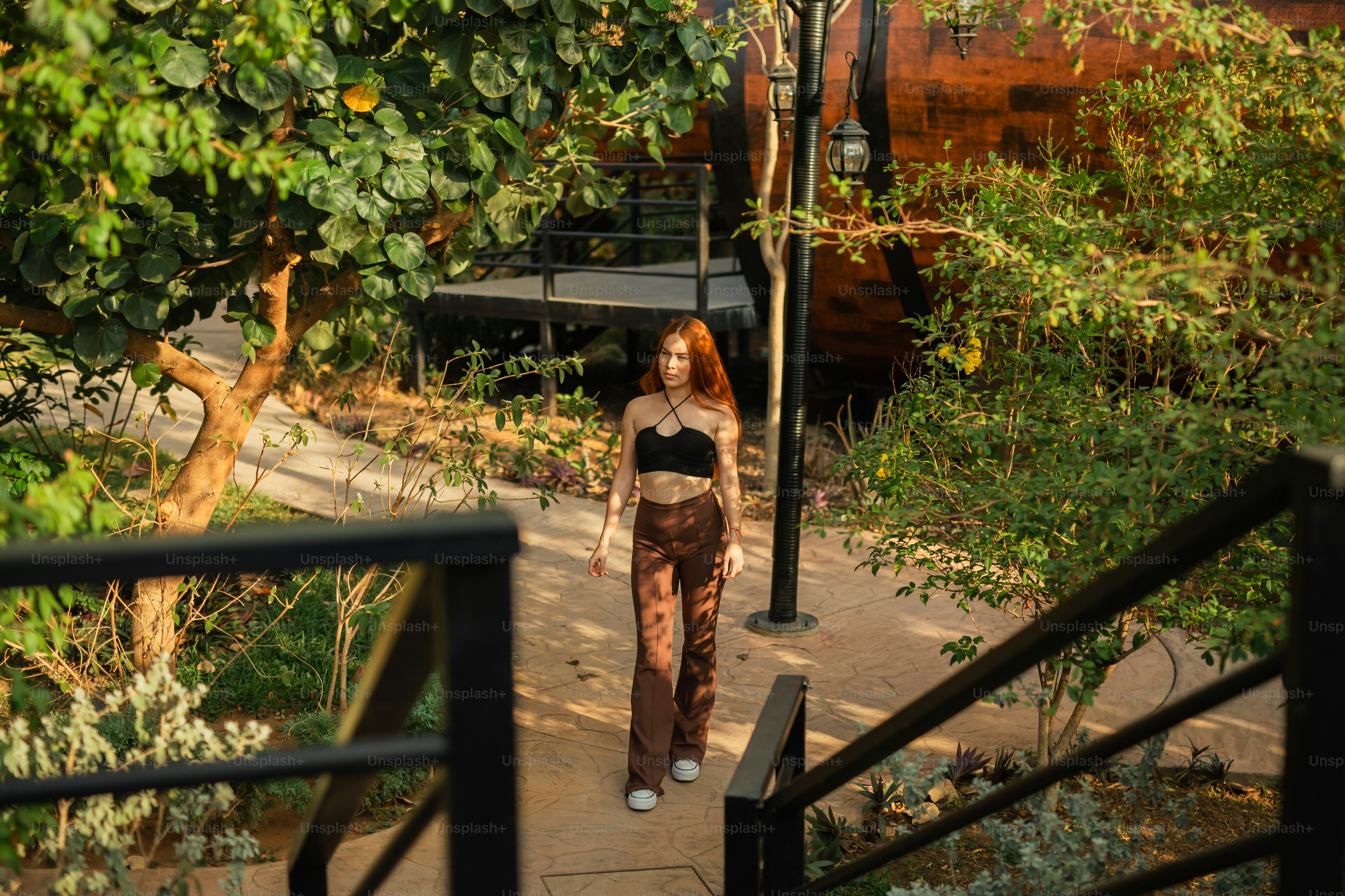uma mulher caminhando por uma calçada ao lado de uma árvore