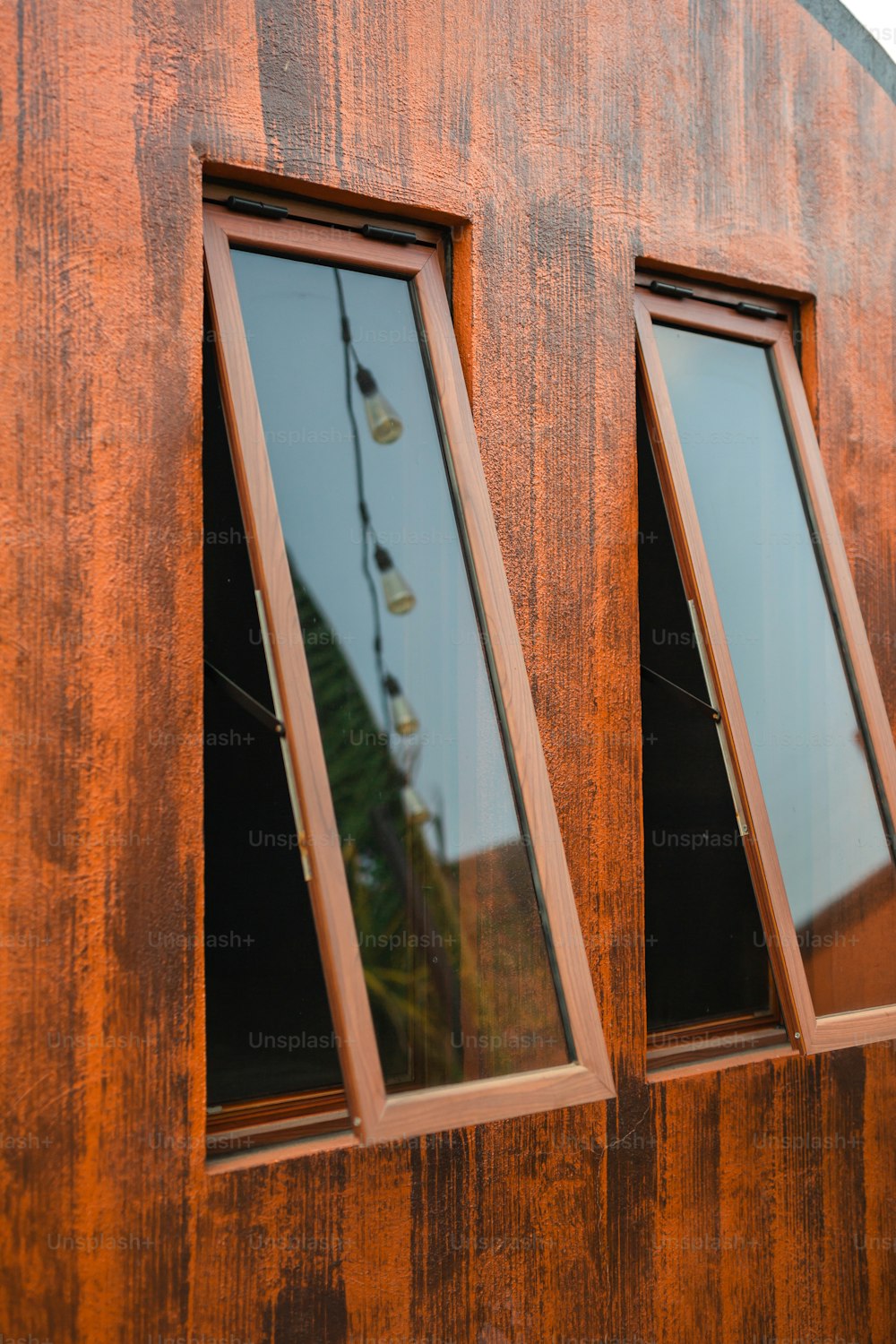 three windows on the side of a wooden building