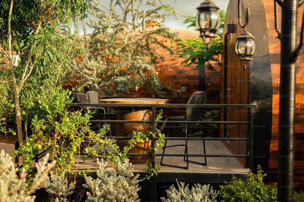 a patio with a table and chairs surrounded by greenery