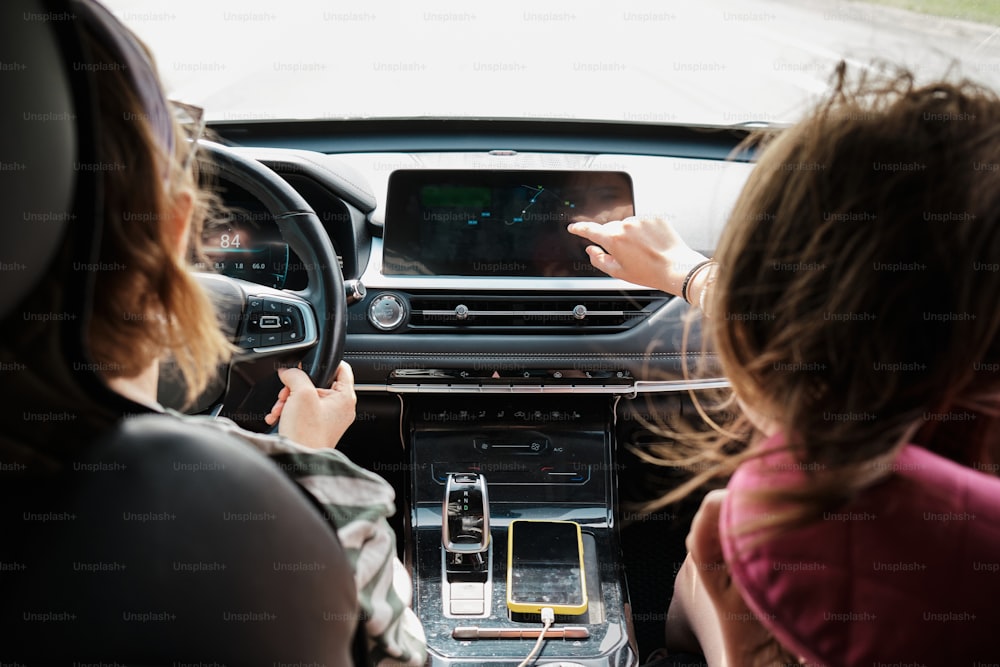 Duas mulheres estão sentadas em um carro e uma delas está segurando um celular