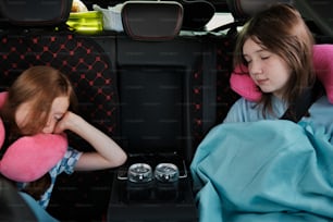 two young girls sitting in the back of a car