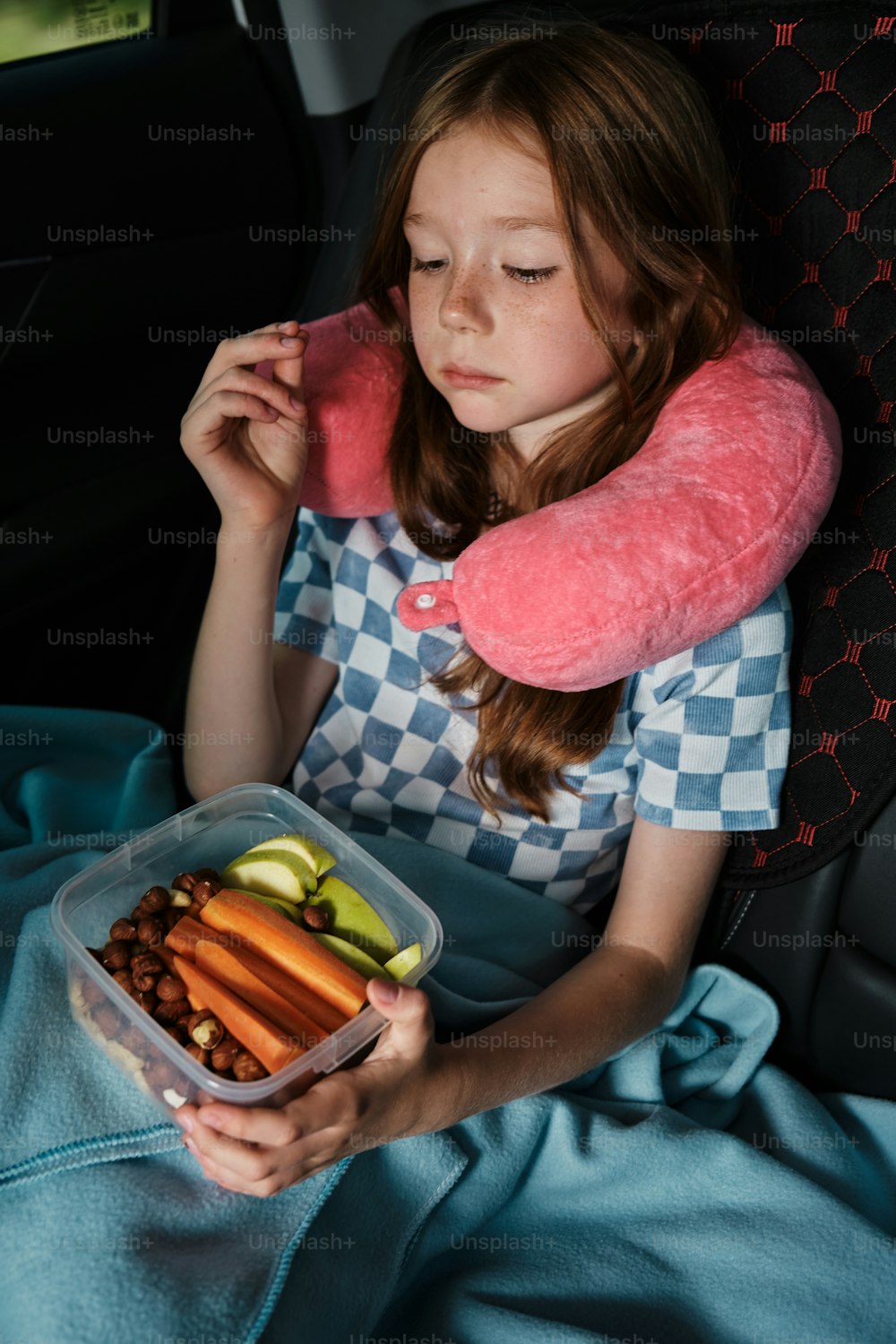 a little girl sitting in a car holding a tray of food