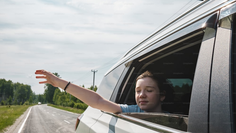 a woman holding out her hand out of a car window