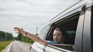 a woman holding out her hand out of a car window