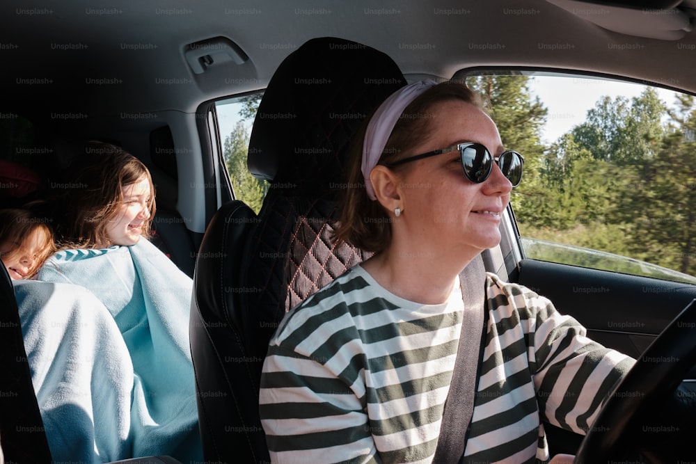 a woman driving a car with another woman in the back seat