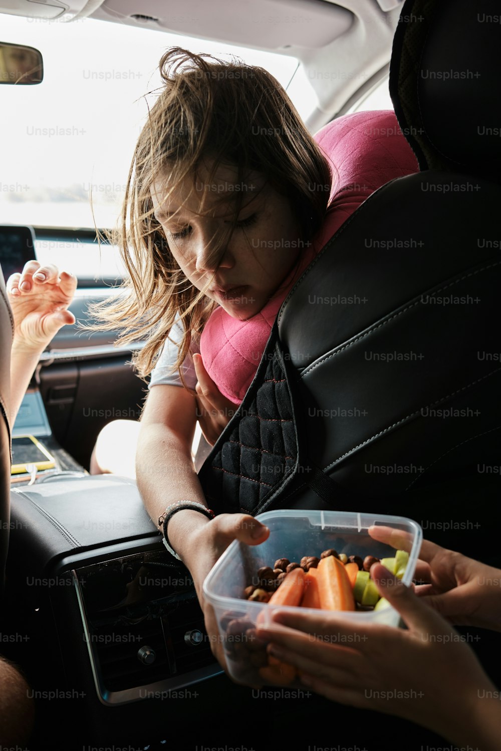 a little girl sitting in the back seat of a car