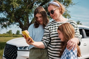 a woman and two girls looking at a cell phone