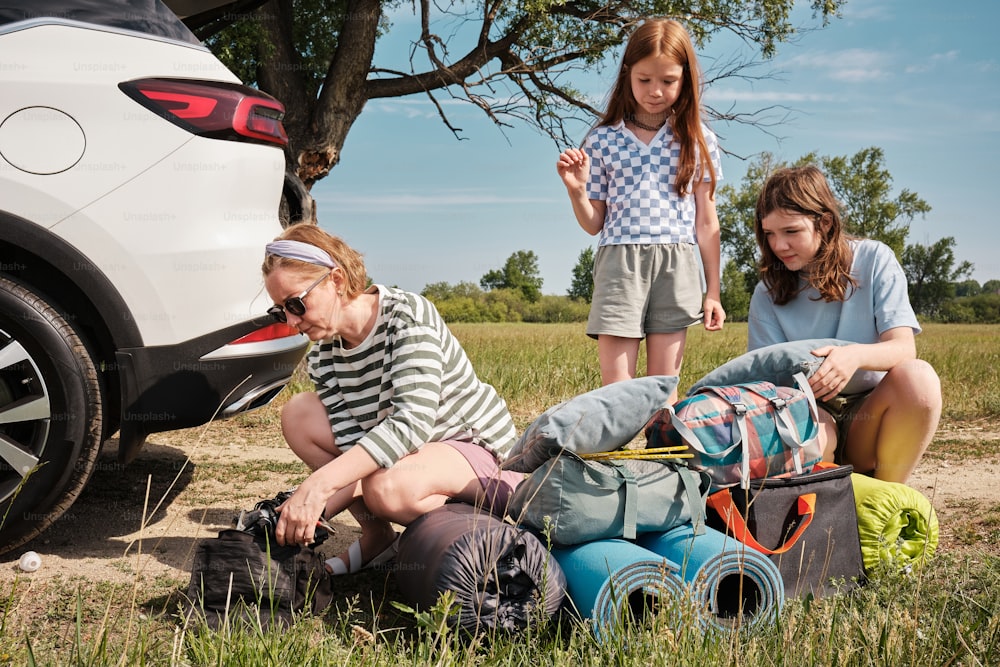 a group of people sitting on the ground next to a car