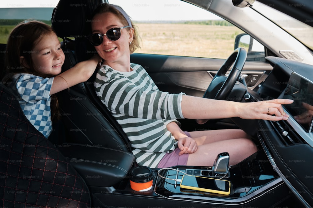 a woman and a little girl sitting in a car