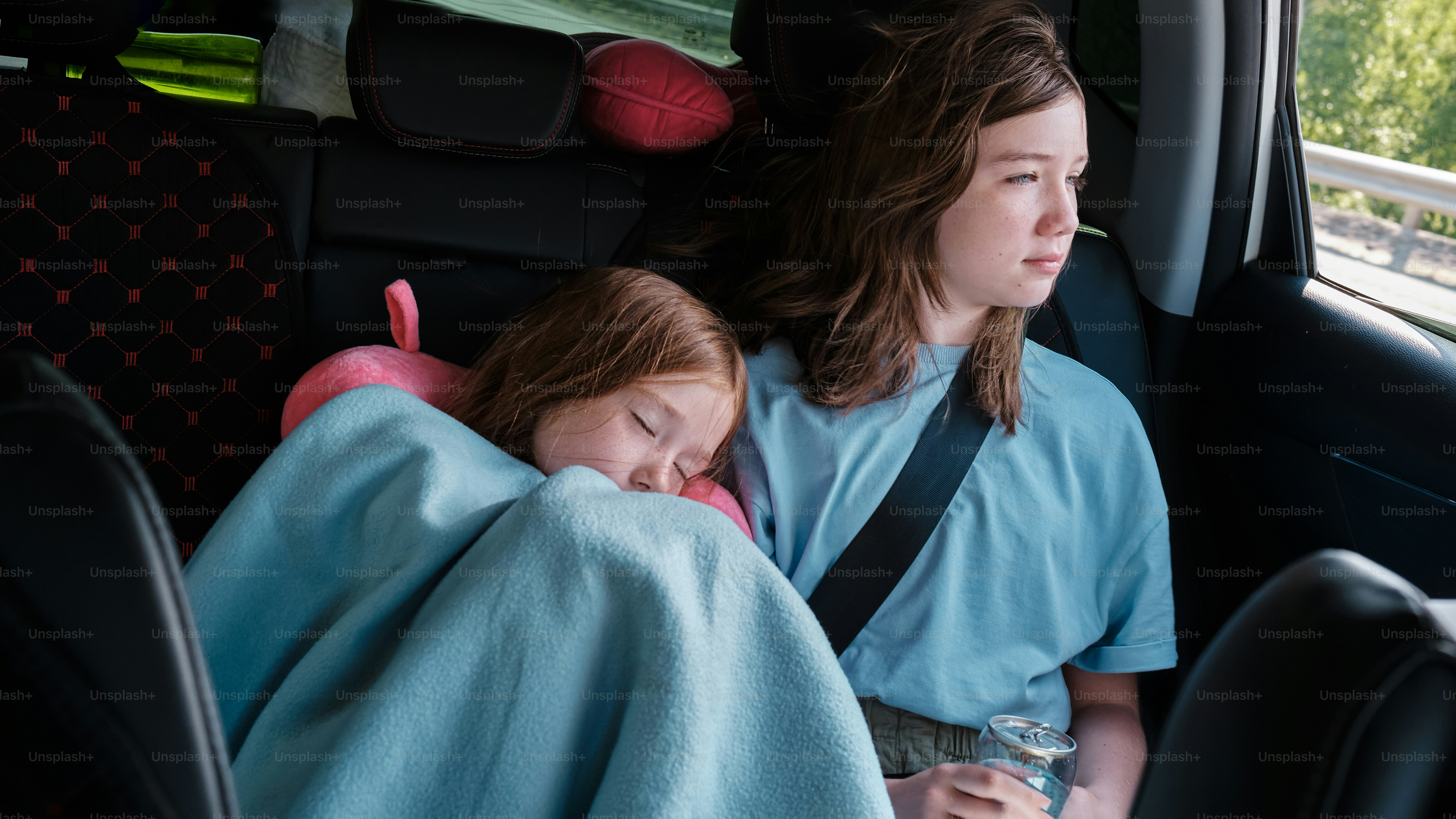 two young girls sitting in the back seat of a car