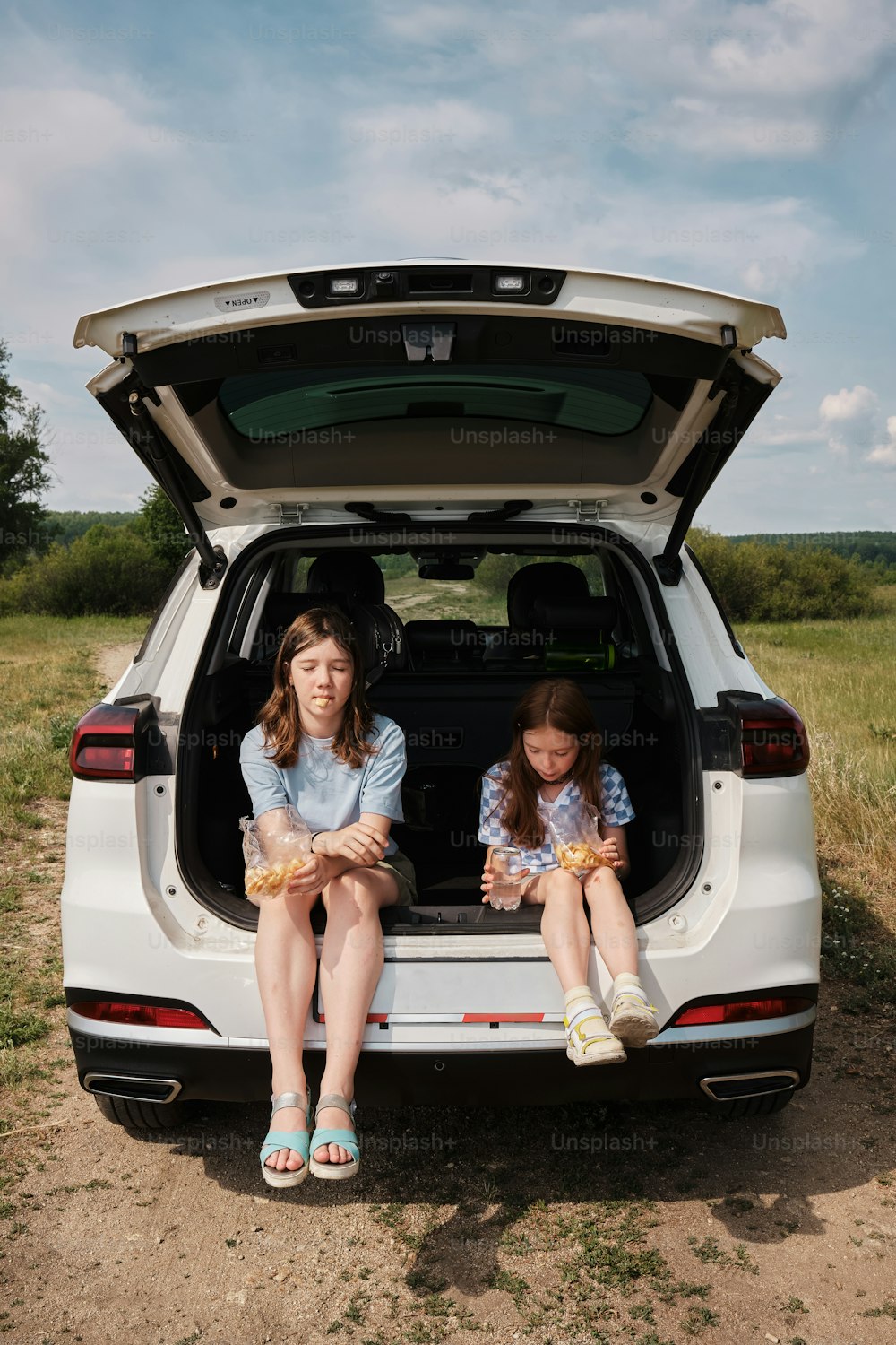 two girls sitting in the back of a white car