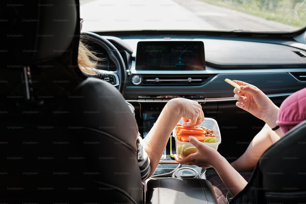 duas pessoas sentadas em um carro comendo cenouras
