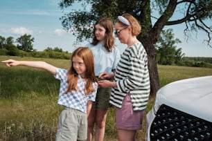 Un groupe de jeunes femmes debout à côté d’une voiture blanche