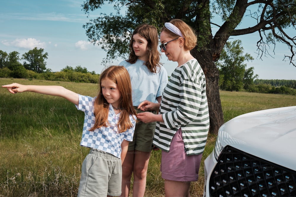 Un grupo de mujeres jóvenes de pie junto a un coche blanco