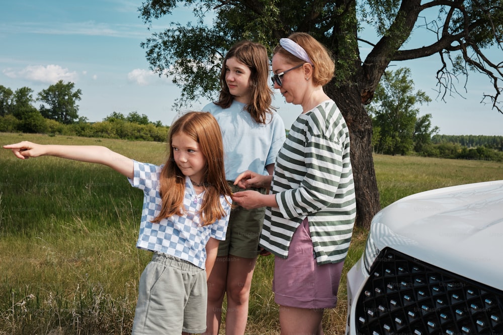 a group of young women standing next to a white car