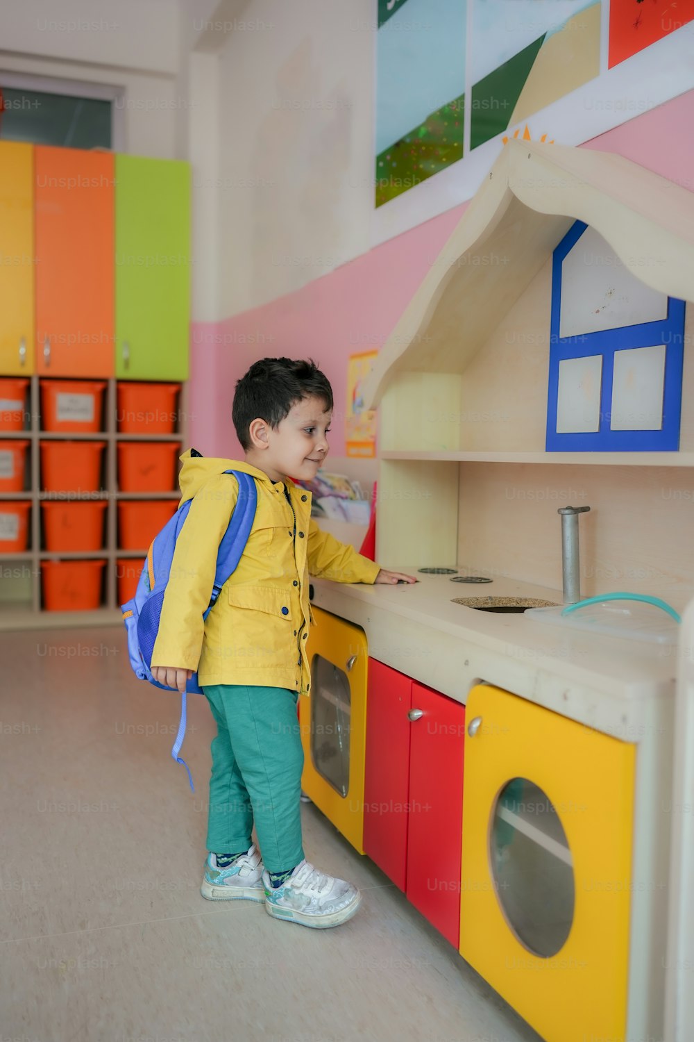 a little boy that is standing in front of a play kitchen