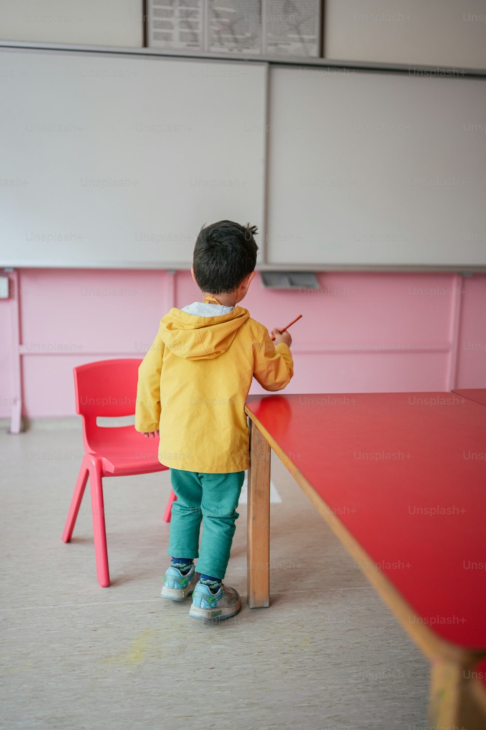 a little boy standing at a red table