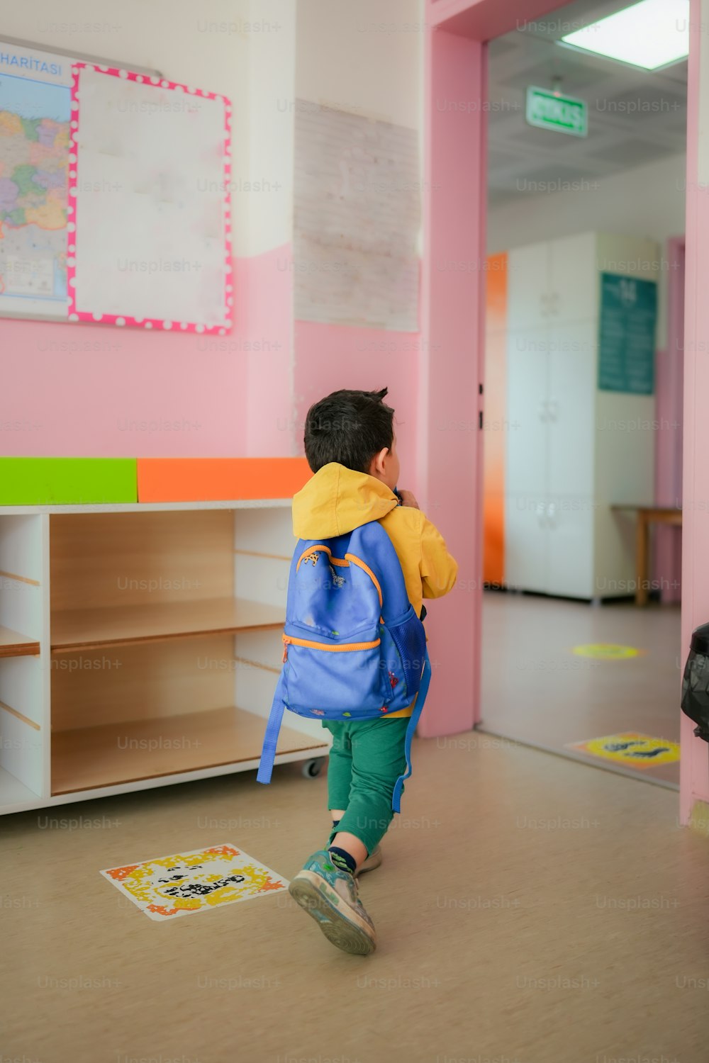 a little boy with a blue backpack walking through a room