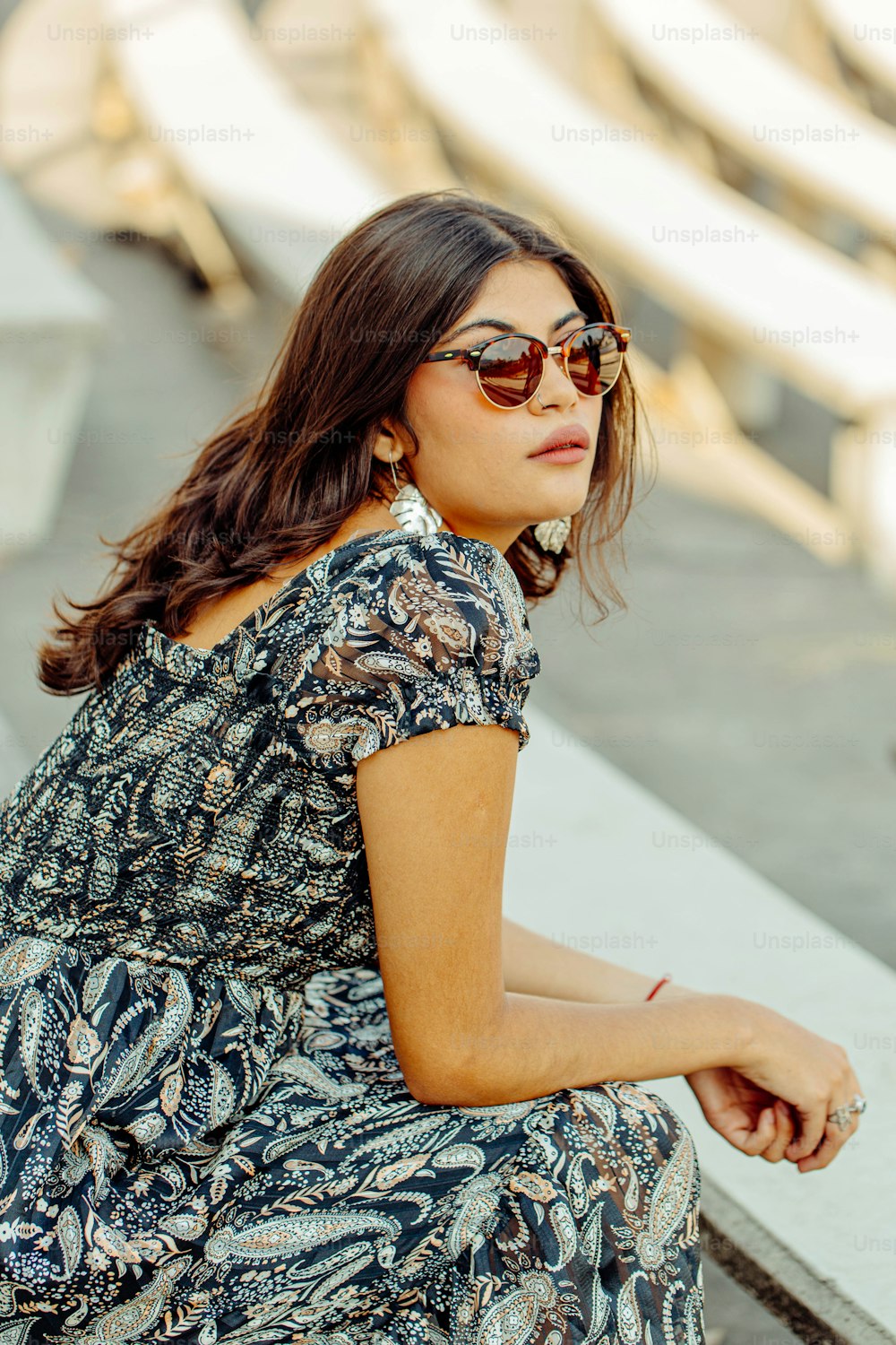 a woman sitting on a bench wearing sunglasses