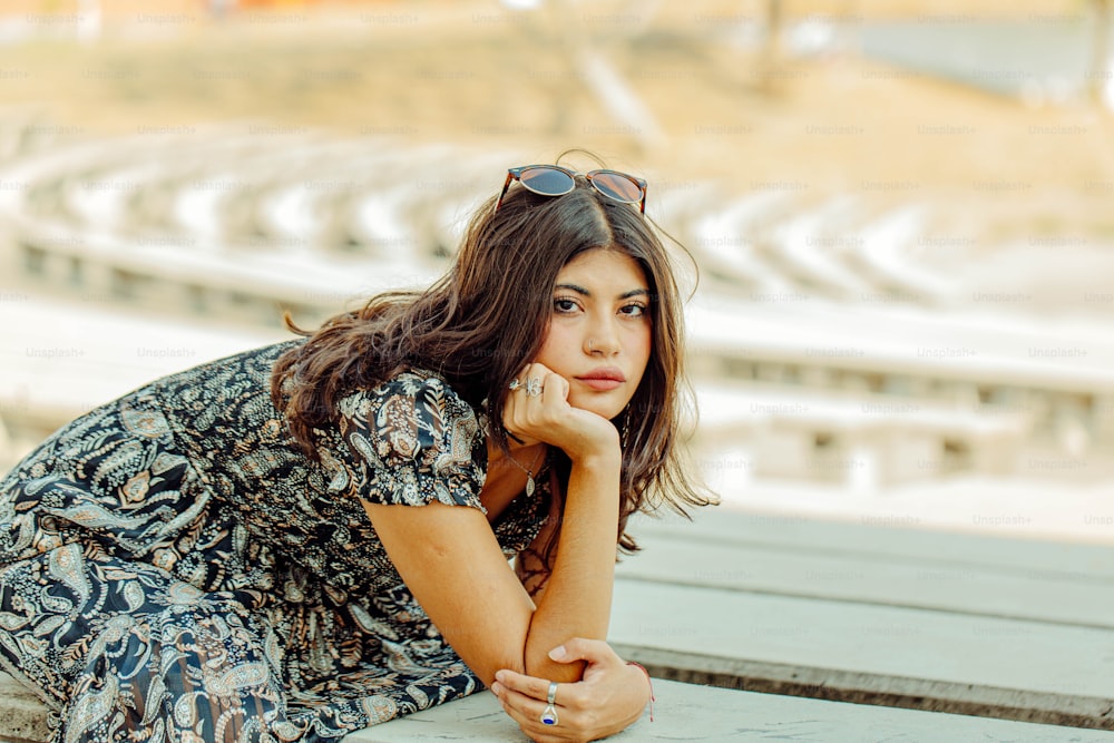 a woman leaning on a bench in front of a stadium