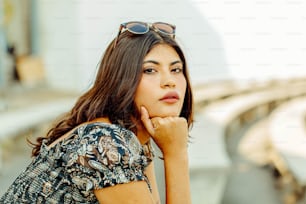 a woman wearing sunglasses is leaning on a wall