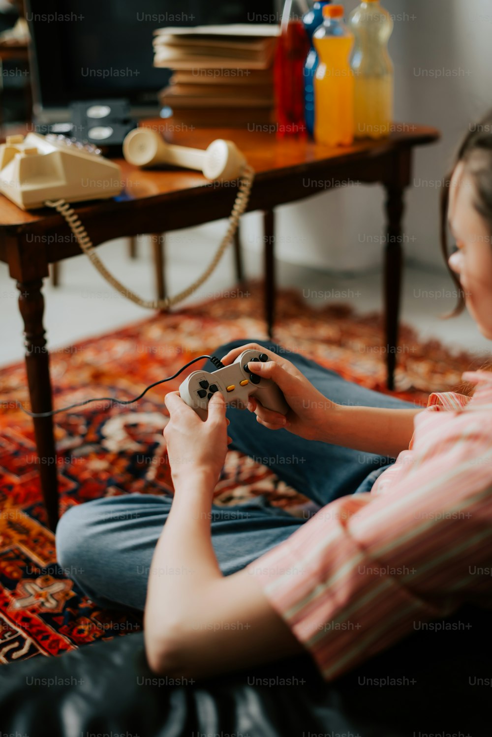 Une femme assise par terre en train de jouer à un jeu vidéo