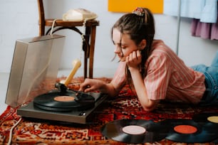 a little girl laying on the floor next to a record player