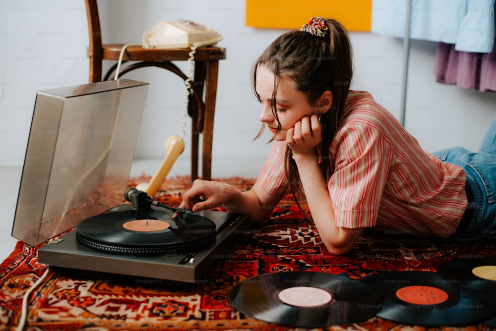 a little girl laying on the floor next to a record player
