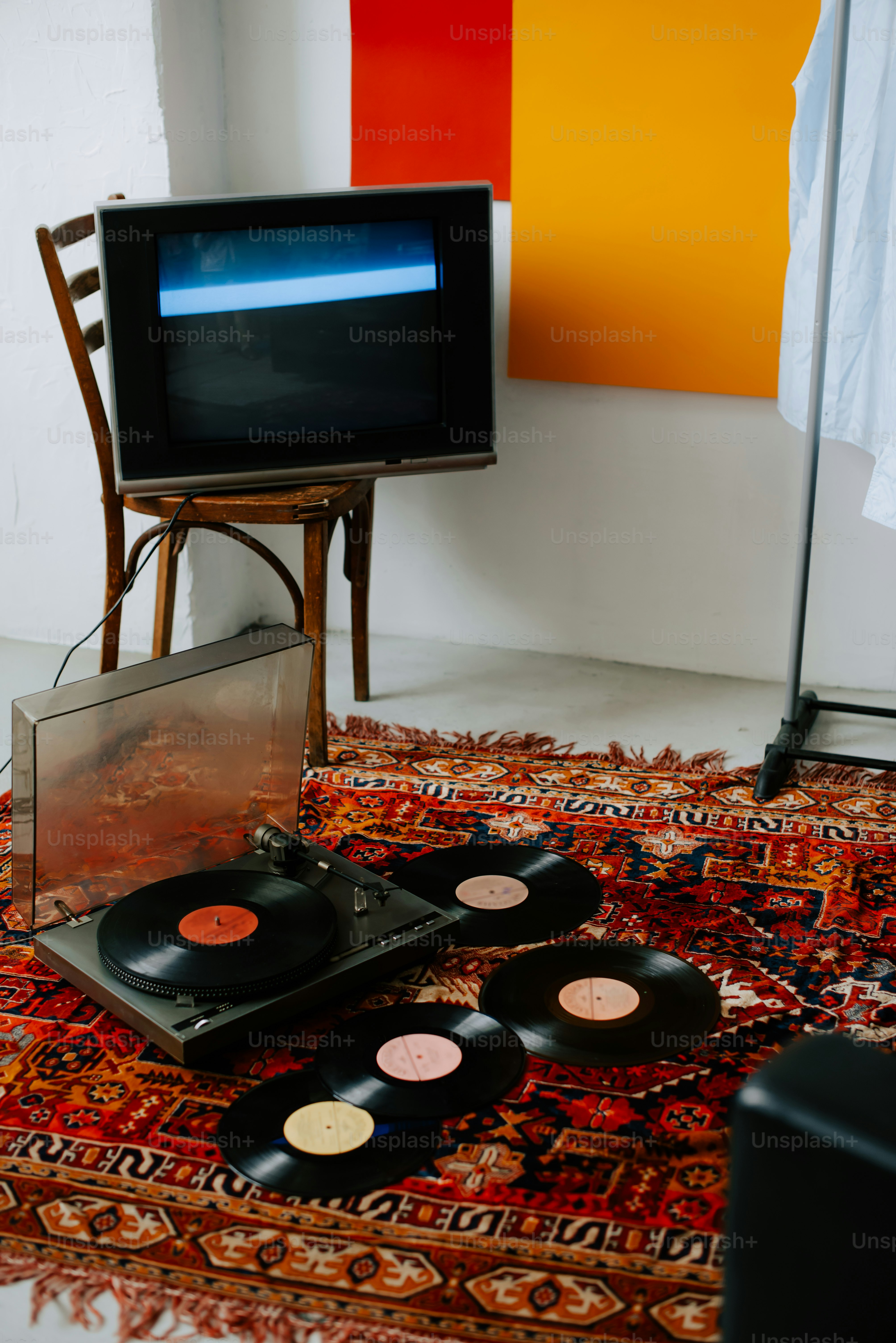 a television sitting on top of a rug next to a record player