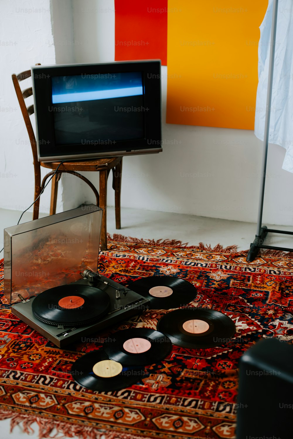 uma televisão sentada em cima de um tapete ao lado de um toca-discos