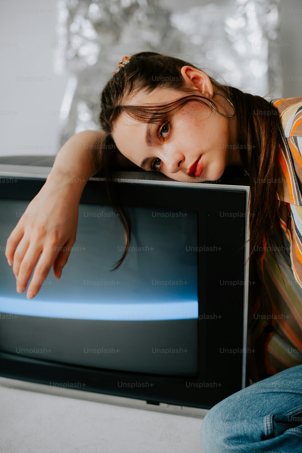 a woman leaning on a television with her head on her hand