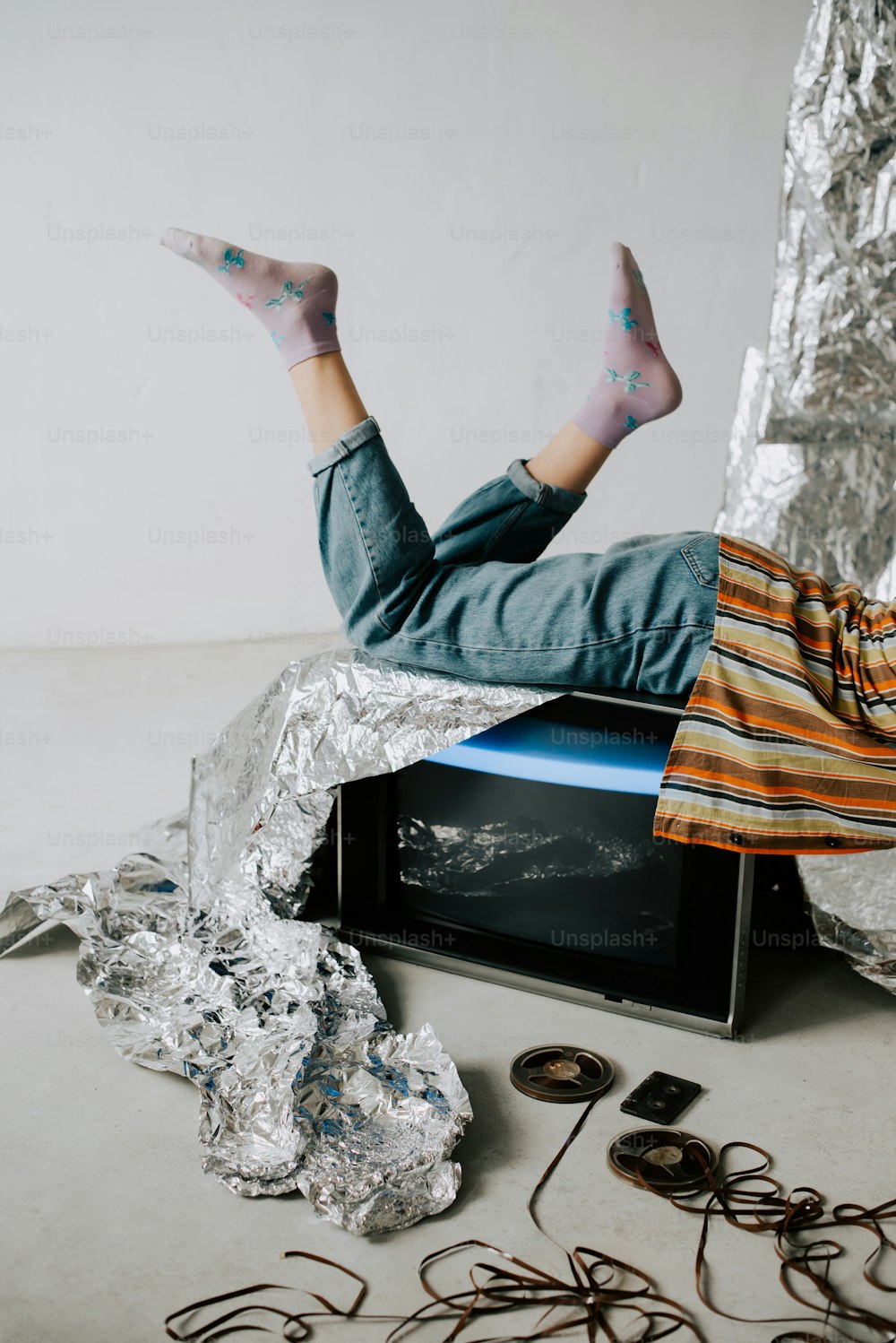 a man laying on top of a microwave covered in tin foil