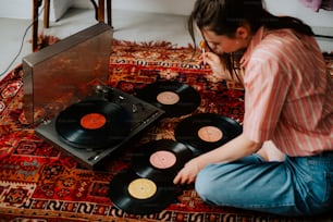 a woman sitting on the floor next to a record player