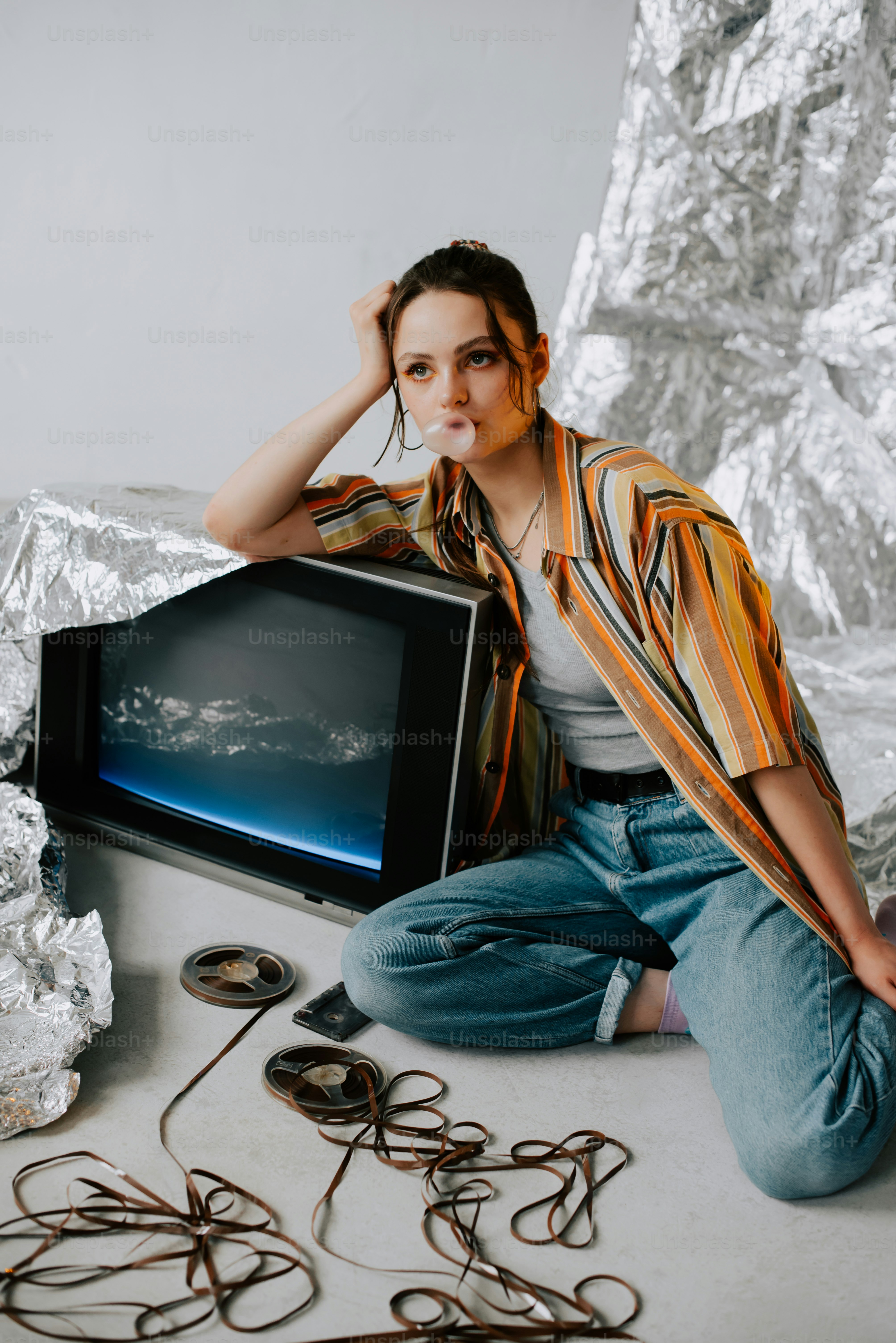 a woman sitting on the floor next to a tv