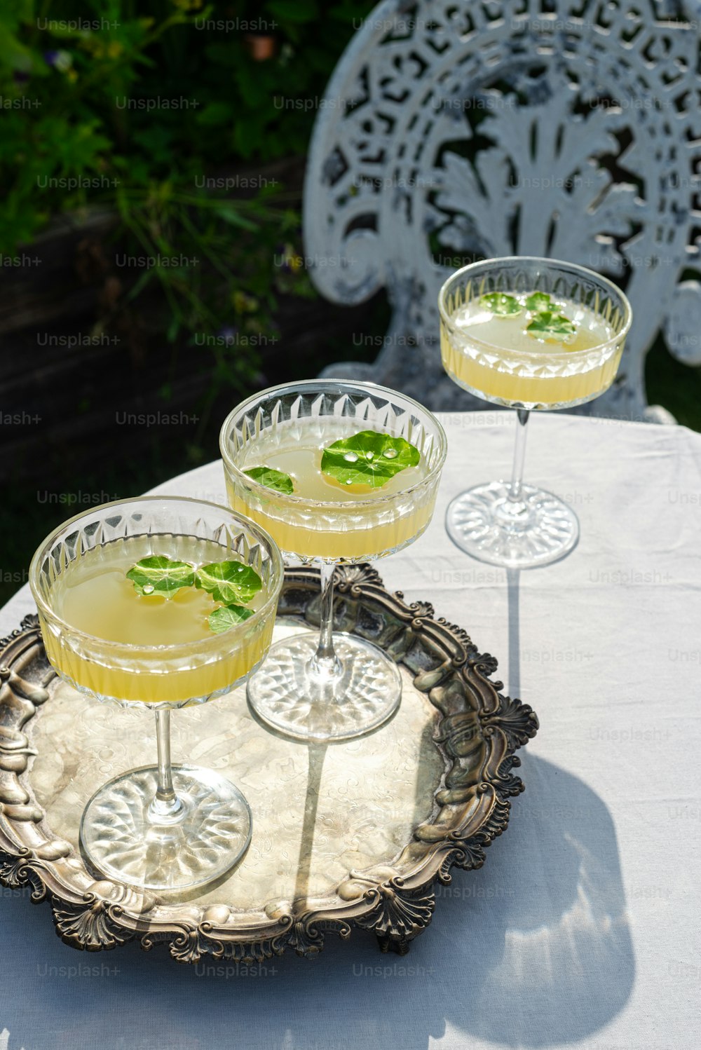 three glasses of cocktail on a tray on a table