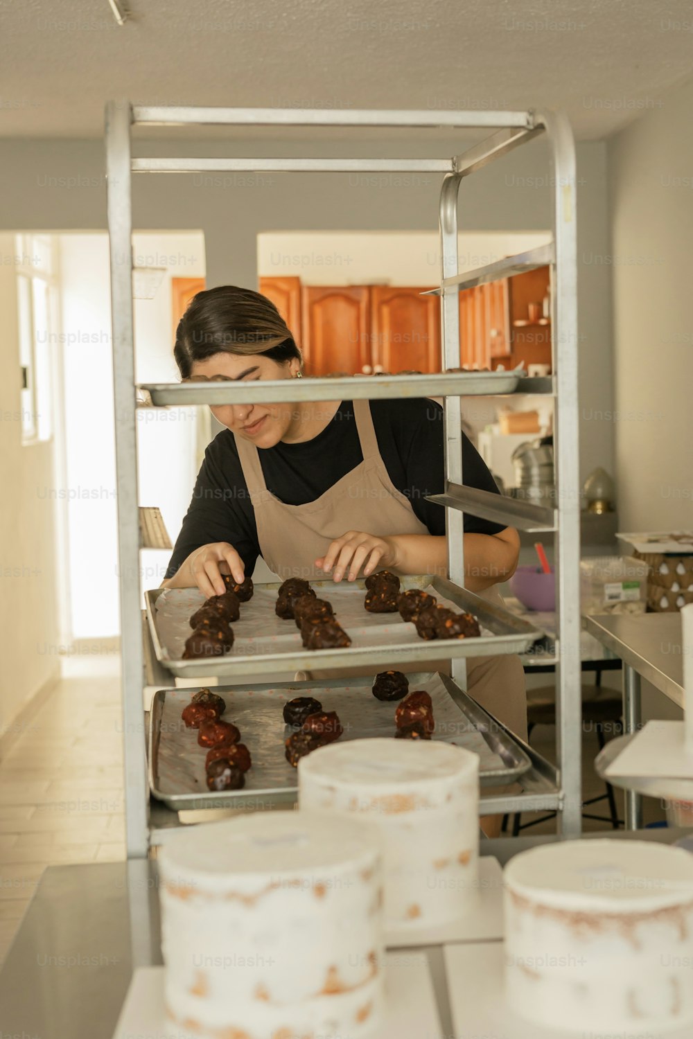 Una mujer en una cocina haciendo donas en un estante