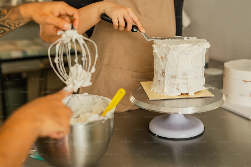 a woman is decorating a cake with icing