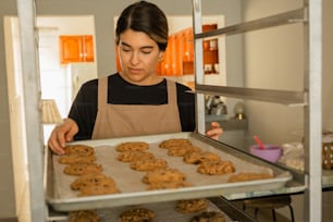 a woman holding a tray of cookies in a kitchen