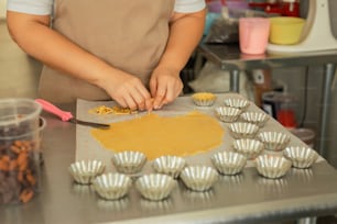 a woman in an apron is making cupcakes