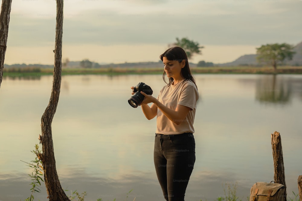 a woman holding a camera near a body of water