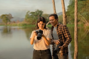 a man and a woman standing next to each other holding a camera