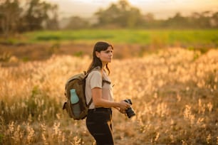 a woman with a backpack and a camera in a field