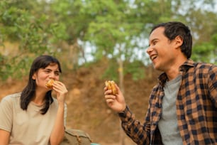 a man and a woman eating food in the woods