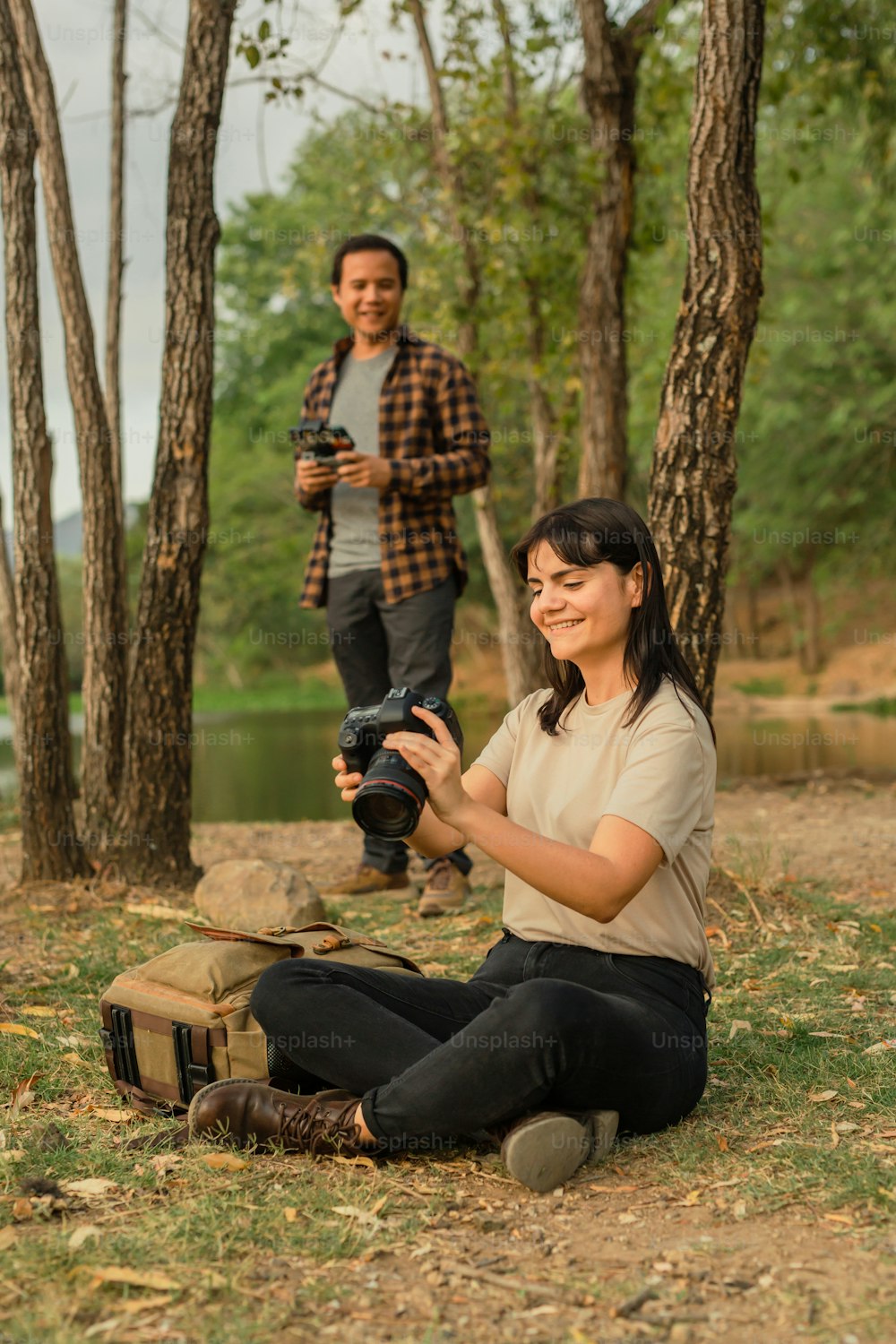 Una donna seduta a terra con in mano una macchina fotografica